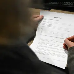 Ein Jagdpachtvertrag wird von einer Hand gehalten, die einen Stift führt. Der Text erwähnt den entgeltlichen begehungsschein.