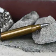 Eine Patrone 6,5x57 liegt auf Steinen. Sie ist bereit für die Jagd auf Schwarzwild.