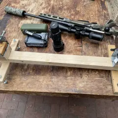 Selbstgebaute Gewehrauflage aus Holz und Metallteilen, daneben ein Jagdgewehr mit Schalldämpfer, Zielfernrohr und Wärmebildgerät.