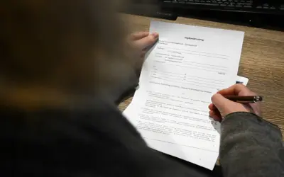 Ein Jagdpachtvertrag wird von einer Hand gehalten, die einen Stift führt. Der Text erwähnt den entgeltlichen begehungsschein.