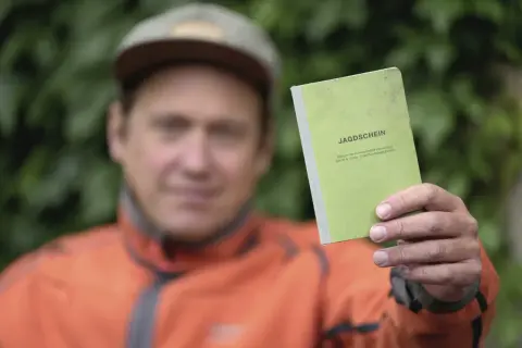 Mann hält grünen Jagdschein in die Kamera. Nach 5 Jahren ist er wieder im Besitz des Dokuments.