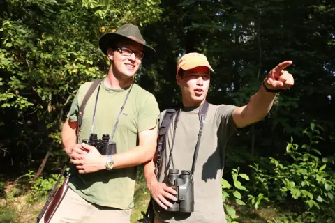 Zwei Männer mit Ferngläsern im Wald, bereit für die Jagd. Sie sind Teil des Landesjagdverbands Hamburg.