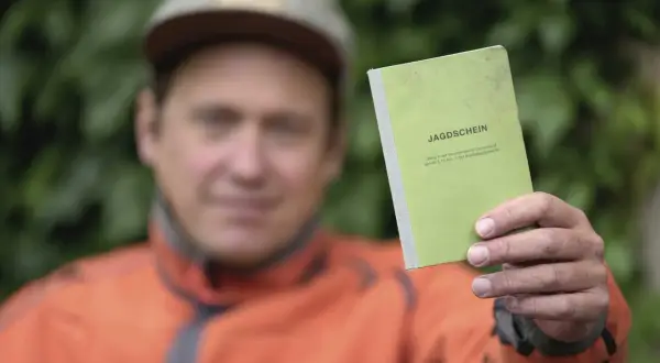 Mann hält grünen Jagdschein in die Kamera. Nach 5 Jahren ist er wieder im Besitz des Dokuments.