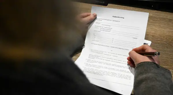 Ein Jagdpachtvertrag wird von einer Hand gehalten, die einen Stift führt. Der Text erwähnt den entgeltlichen begehungsschein.
