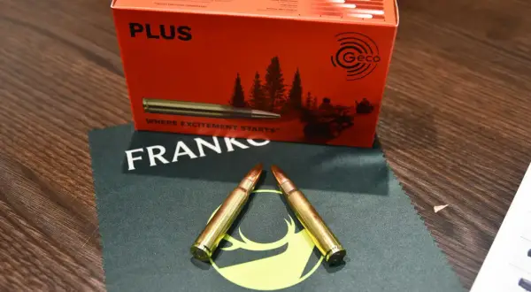 Zwei Patronen im Kaliber 8x57IS liegen auf einem Tuch. Die Verpackung im Hintergrund verspricht eine gute Reichweite.
