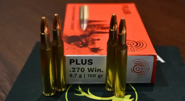 Vier Patronen .270 Win. von Geco liegen neben der orangefarbenen Packung. Ideal für die Jagd auf Schwarzwild.