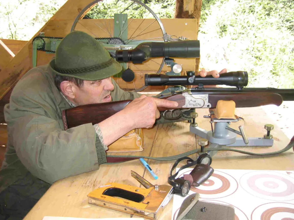 Ein Mann mit Hut zielt mit einem Gewehr mit kurzem Lauf. Auf dem Tisch liegen ein Tacker und Zielscheiben.