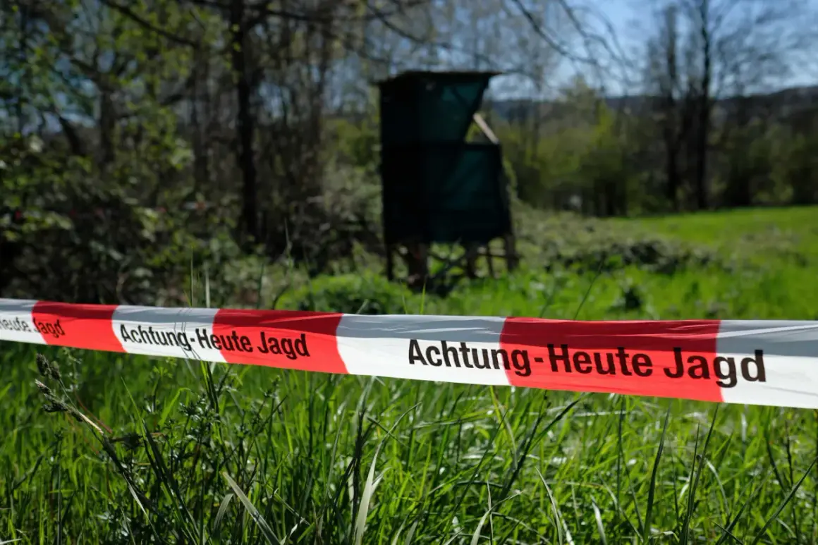 Absperrband mit der Aufschrift "Achtung - Heute Jagd" im Vordergrund. Im Hintergrund ein Hochsitz und Bäume.