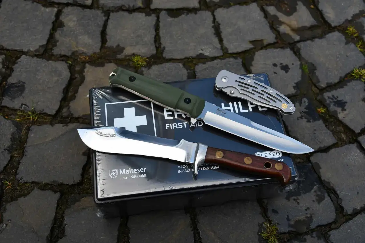Zwei Messer, ein Jagdmesser und ein Klappmesser, liegen auf einer Erste-Hilfe-Box. Beachten Sie das Waffengesetz.