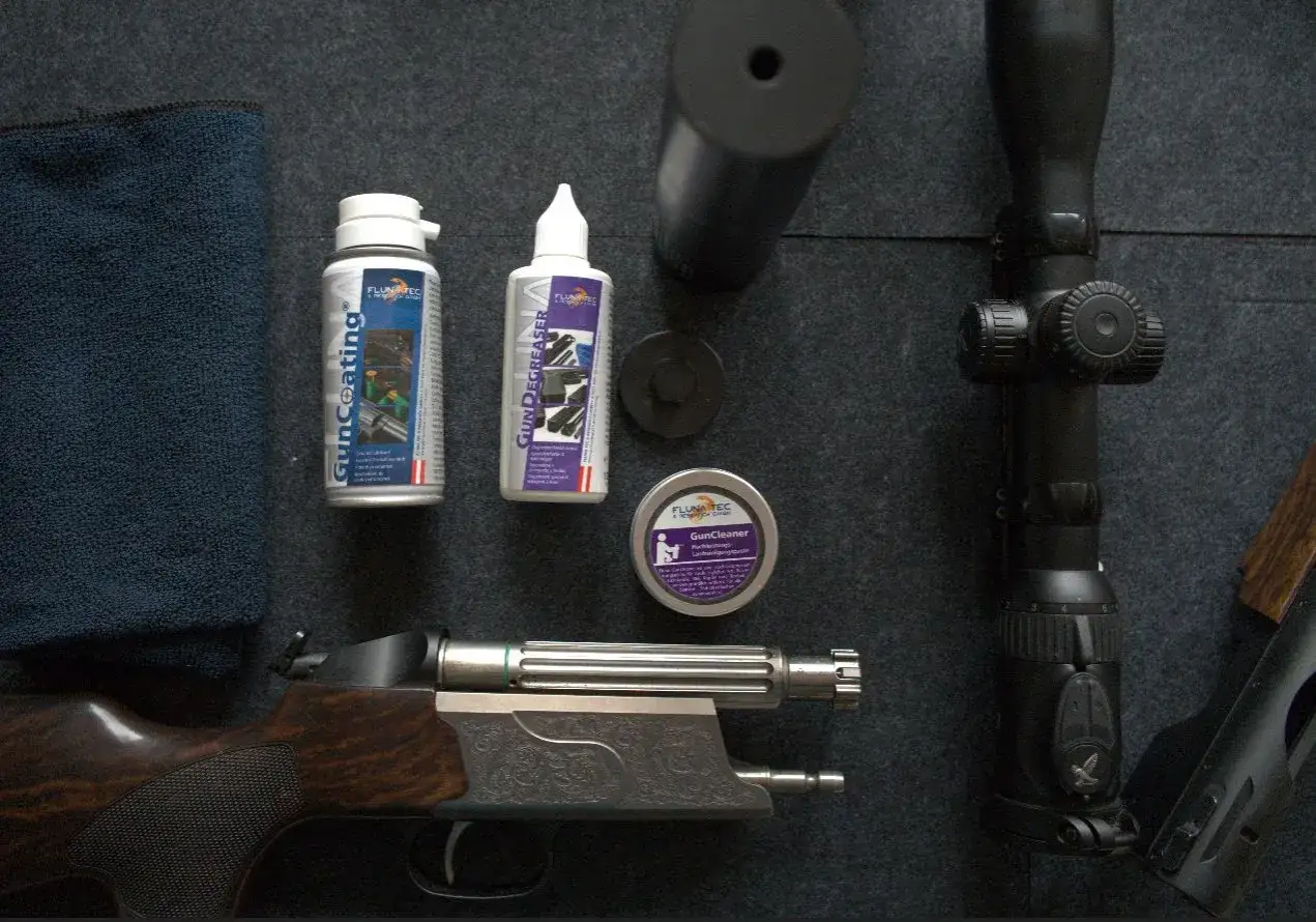 Fluna Tec Gun Coating und Zubehör für die Waffenpflege. Ein Gewehr, ein Zielfernrohr und Reinigungsmittel liegen bereit.