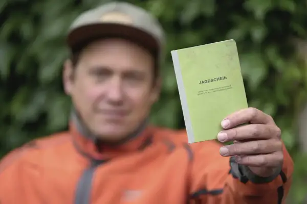 Mann hält grünen Jagdschein in die Kamera. Nach 5 Jahren ist er wieder im Besitz des Dokuments.