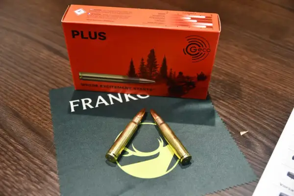 Zwei Patronen im Kaliber 8x57IS liegen auf einem Tuch. Die Verpackung im Hintergrund verspricht eine gute Reichweite.